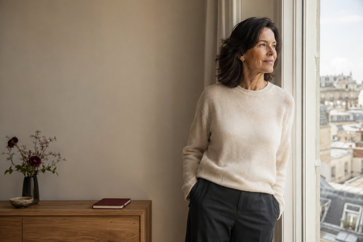 A confident woman in midlife looking out from a sunlit window